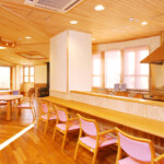 デイサービスのオープンキッチンカウンターの様子。手前はカウンター、奥に見えるのは薪ストーブです。簡単な調理や盛り付け、片付けなどの場面で高齢者が参加することもできます。